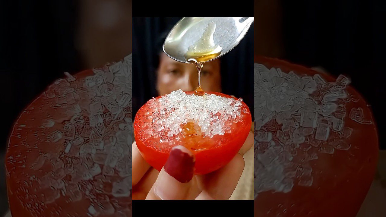 Pusė pomidoro su druska ant viršaus ir medus leistas šaukštu virš jo