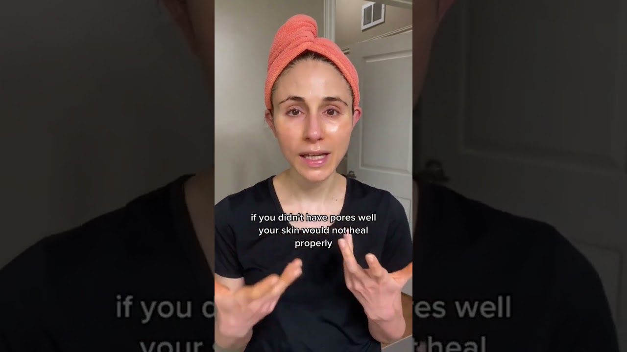 Moteris su oranžiniu rankšluosčiu ant galvos aiškina odos priežiūrą, ekrane užrašas apie poras.