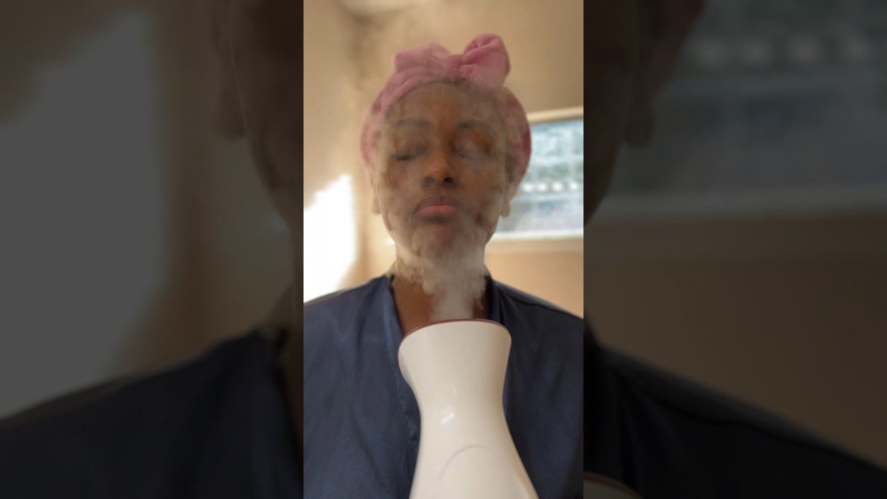 Moters veidas su užmerktomis akimis garinamas veido garų inhaliatoriumi ir rožine galvos juosta