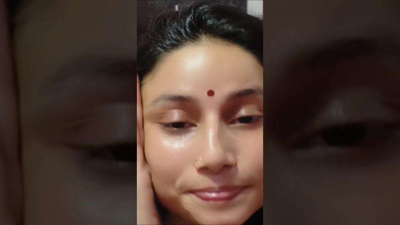 Jauna moteris su raudonu bindi ant kaktos ir ranka laikanti veidą, rami išraiška