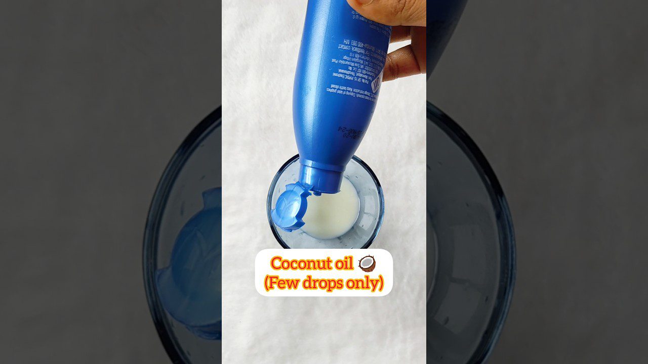 Mėlynas buteliukas lašo kokosų aliejų į stiklą, matomas užrašas „Coconut oil (Few drops only)“