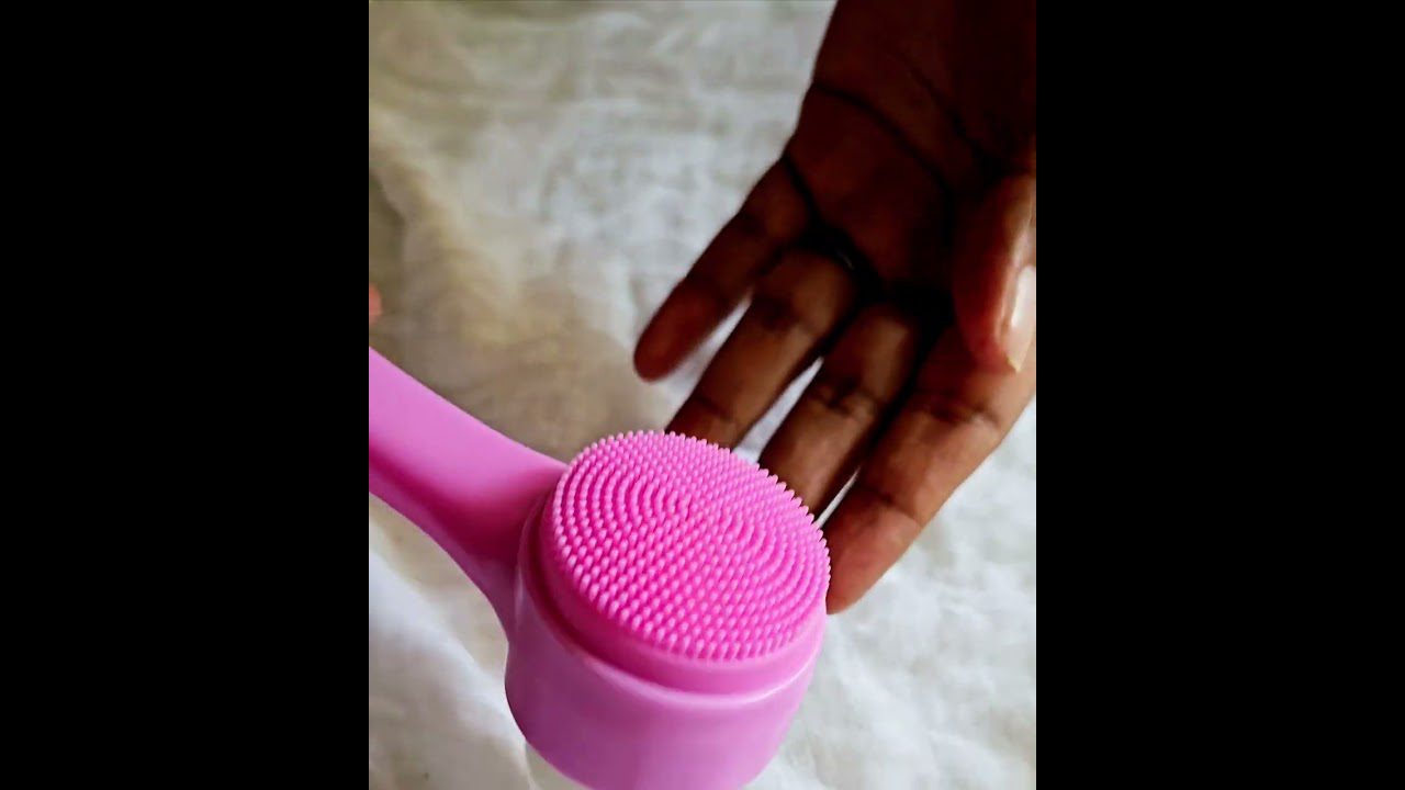 Rožinis silikono veido šepetėlis su smulkiais šereliais prie rankos.