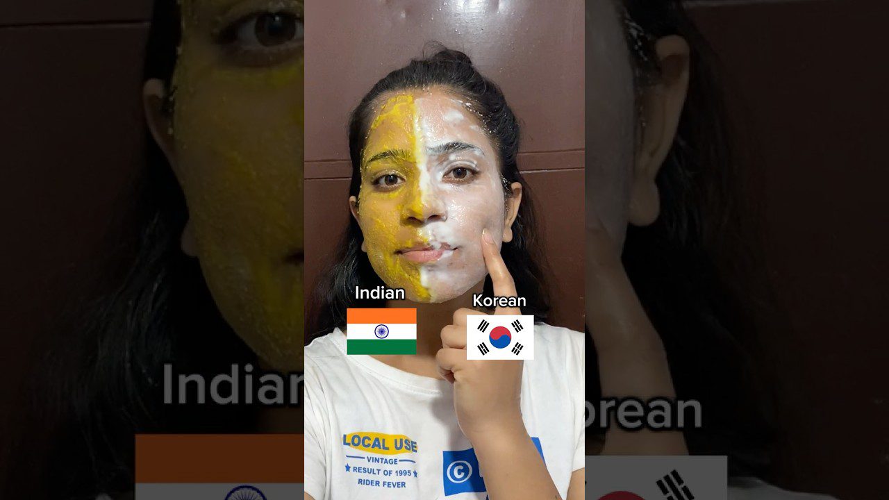 Moteris su veido kauke: kairė pusė geltona (Indijos), dešinė balta (Korėjos), rodo nykščiu.