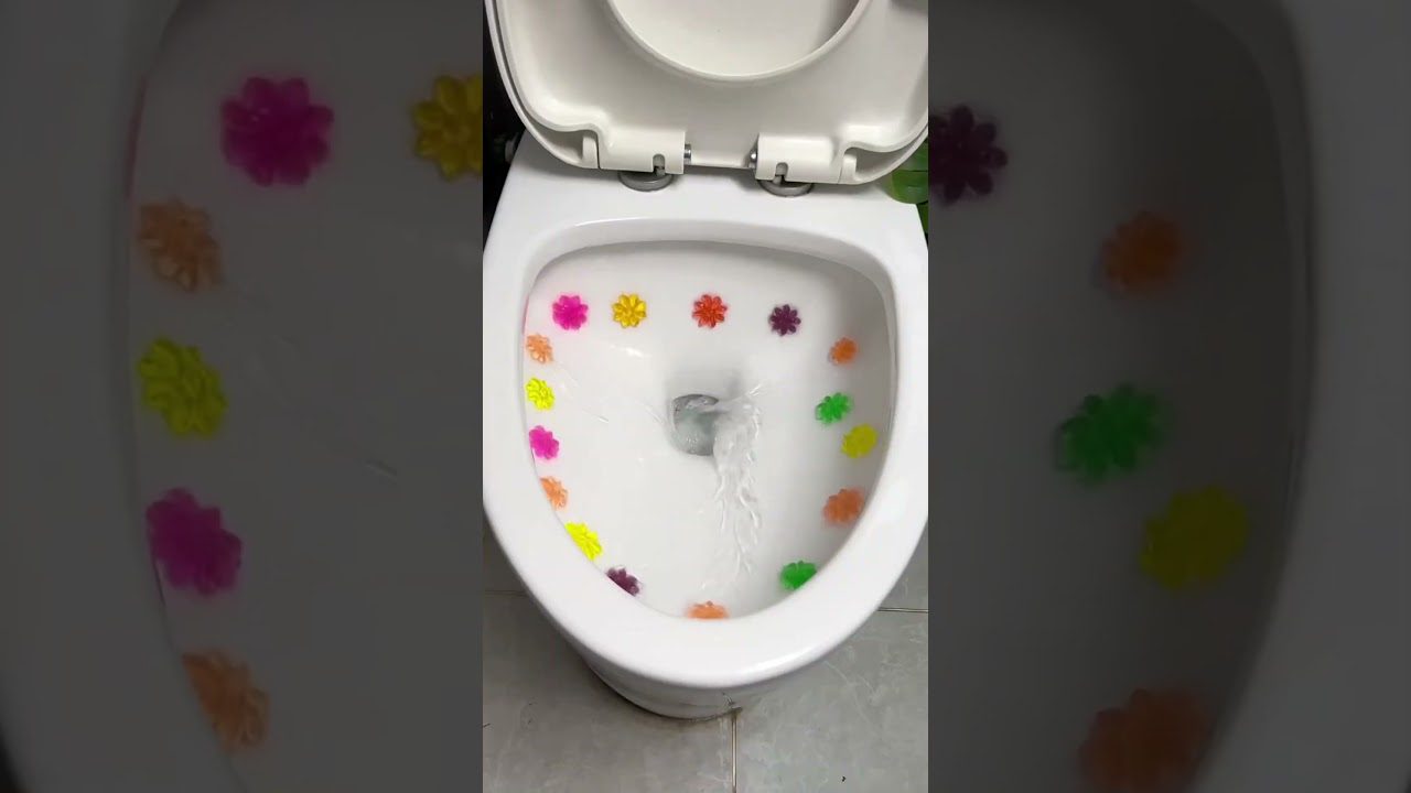 Balti klozeto indai su spalvotomis gelinių gėlių formų lipdukėmis aplink vidų ir tekančiu vandeniu