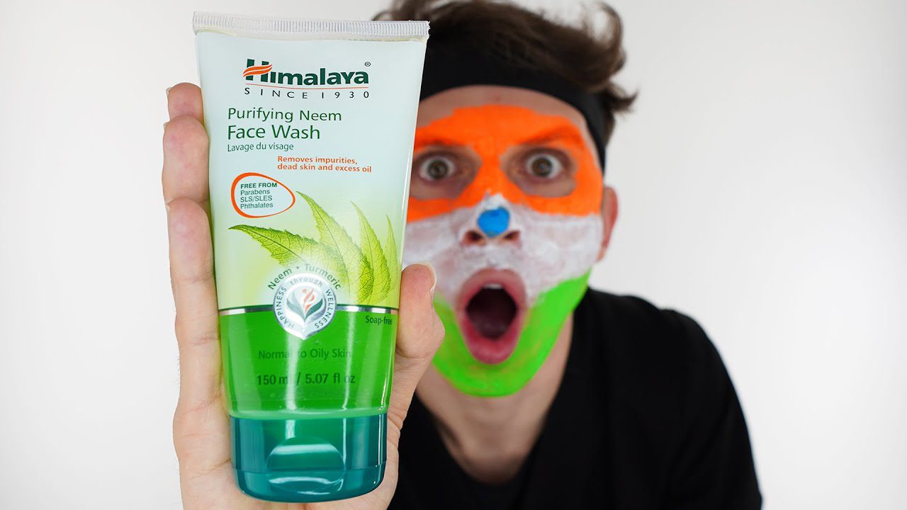 Vyras su trispalve veido kauke laiko „Himalaya Purifying Neem Face Wash“ tūtelę priekyje