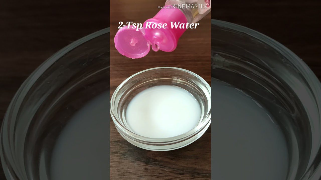 Stiklinis indas su pieno spalvos rožių vandens mišiniu ir rausvo dangtelio buteliukas viršuje, užrašas „2 arbat. š. rožių vanduo“