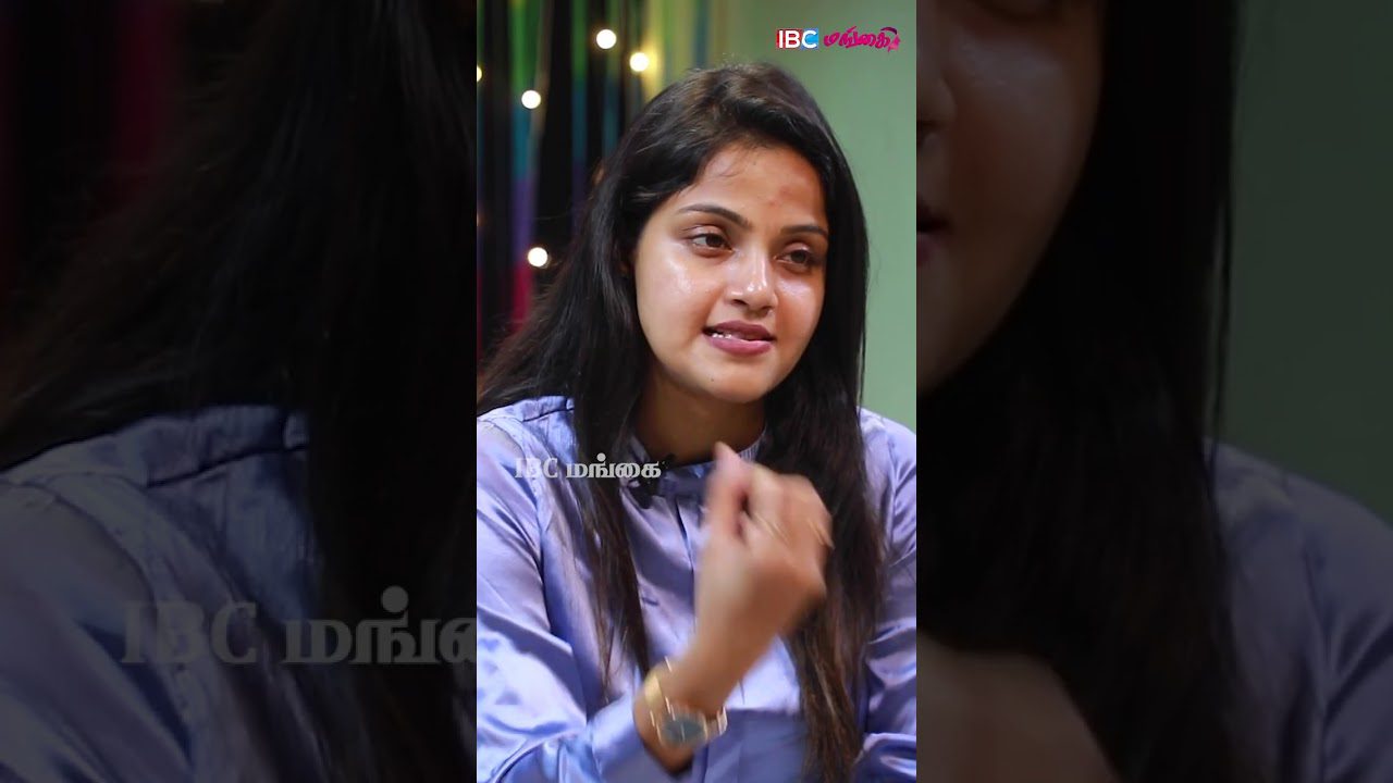 Jauna moteris kalba gestikuliuodama, vilki šviesiai mėlyną satino bluzę.