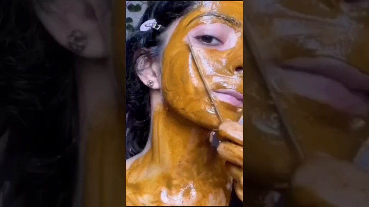 Moteris tepa ant veido ir kaklo geltoną kaukę mentele, matoma pusė veido ir kaklas