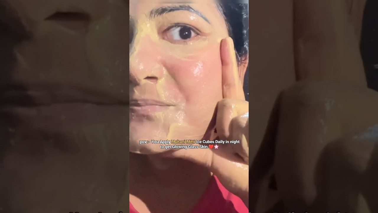 Moteris tepasi žvilgantį gelį ant veido, rodydama pirštu skruostą ir tekstą.