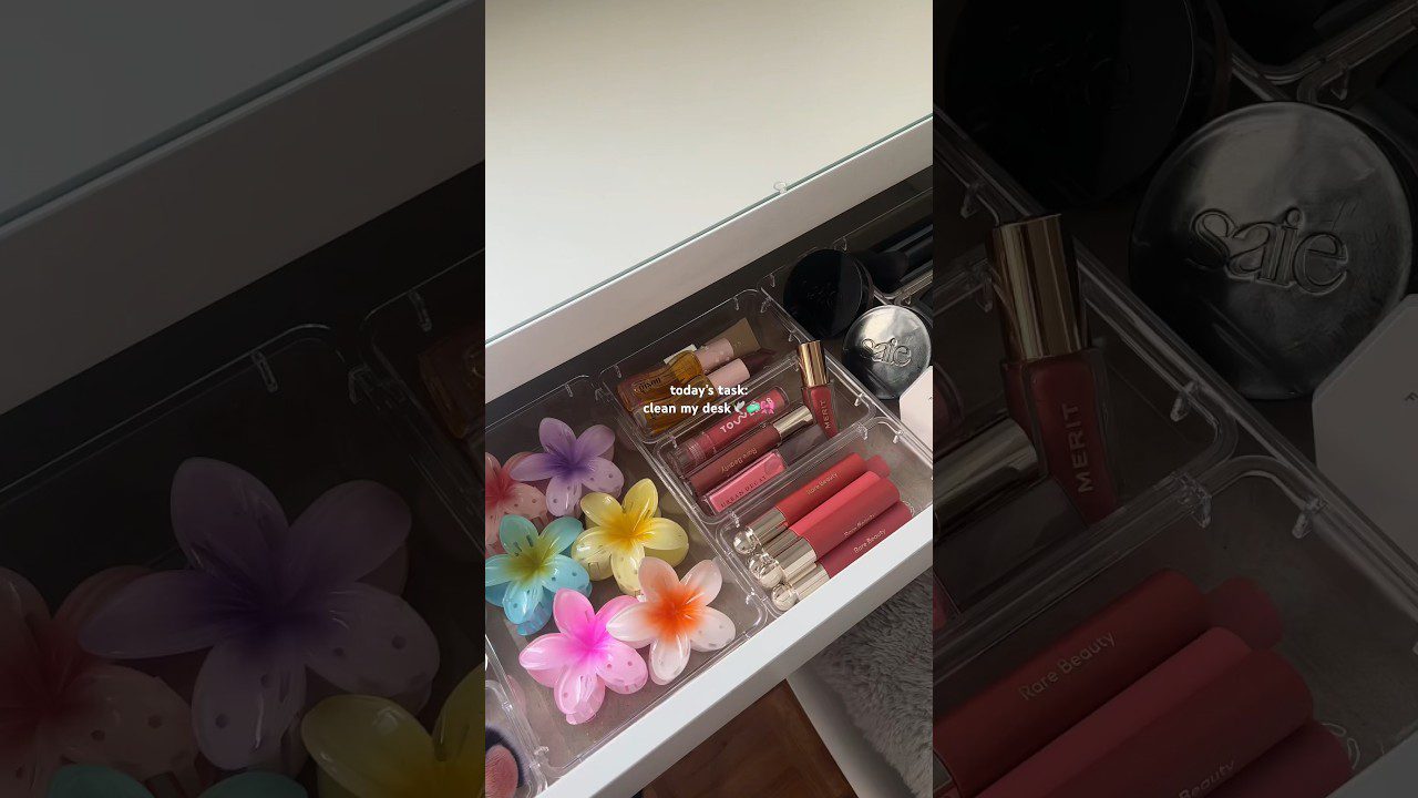 stalčiaus skyrelis su lūpų dažų ir blizgių rinkiniais bei spalvotomis gėlių formos vonios žvakėmis
