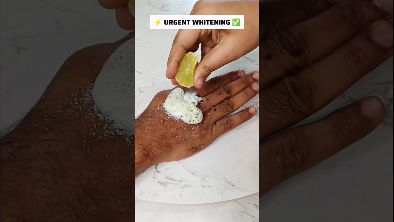 Rankoje dedamas citrinos sulčių lašas ant balto putojančio mišinio ant kitos rankos odos.