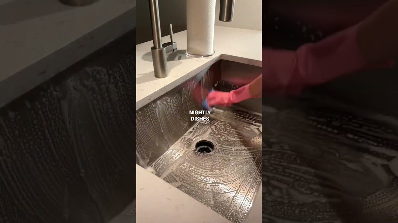 Rankų apsaugos pirštinėmis trinama putojanti nerūdijančio plieno kriauklė su užrašu „nightly dishes“ (vakariniai indai).