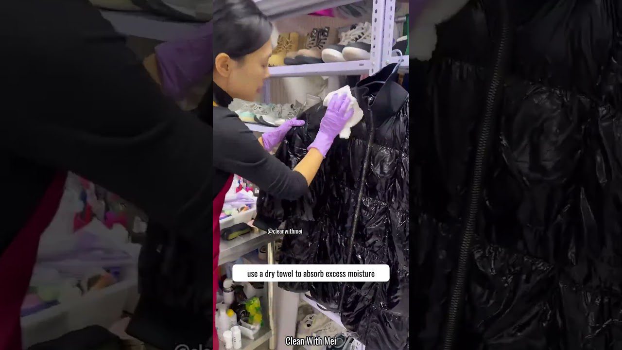 Moteris su purpurinėmis pirštinėmis valo juodą blizgantį pūkinį paltą skudurėliu, lentyna fone.