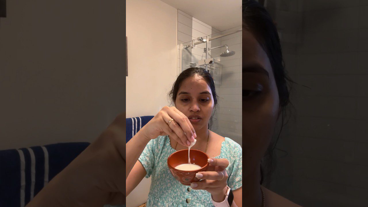 Moteris vonioje lašo pieno arba kremo į mažą dubenėlį, dėvi žalią megztinį