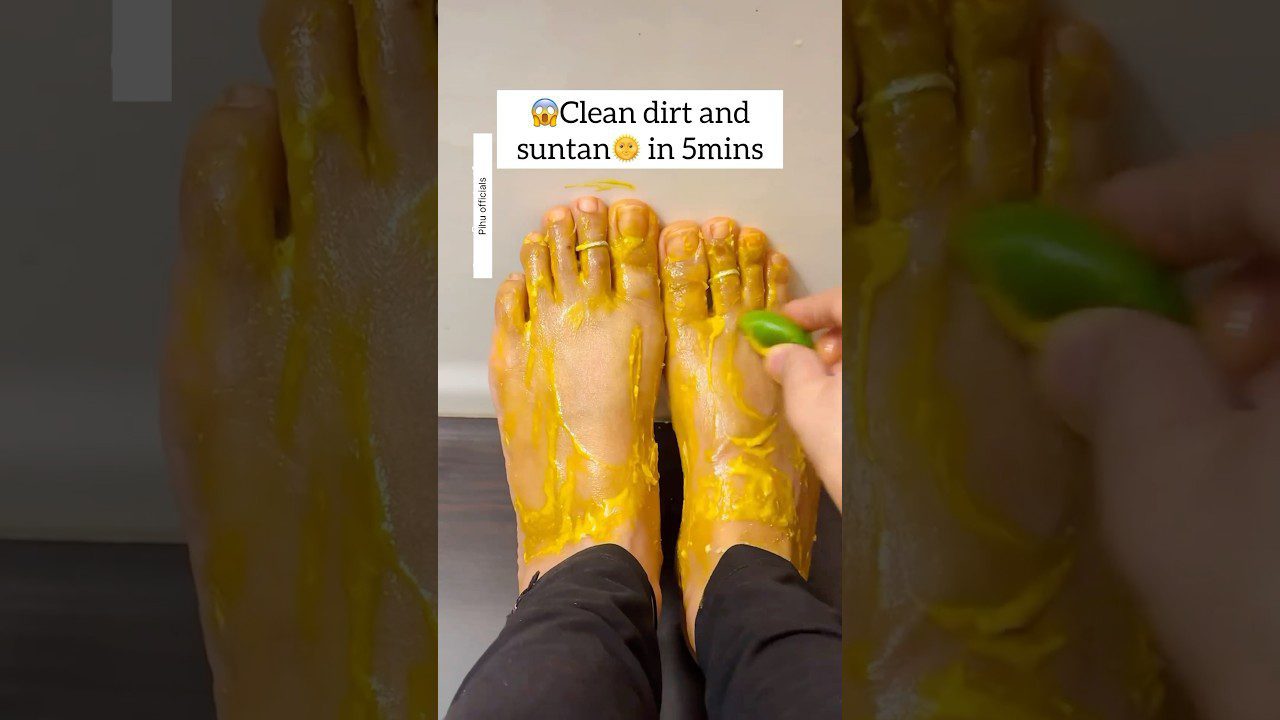 Pėdos padengtos geltonu pasta, žmogus trina jas žalios citrinos gabalėliu.
