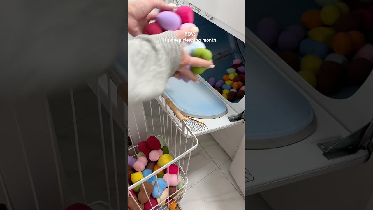 Rankos kiša spalvotas makiažo kempinaites į skalbimo mašinos būgną, šalia metalinis krepšys pilnas kempinaičių