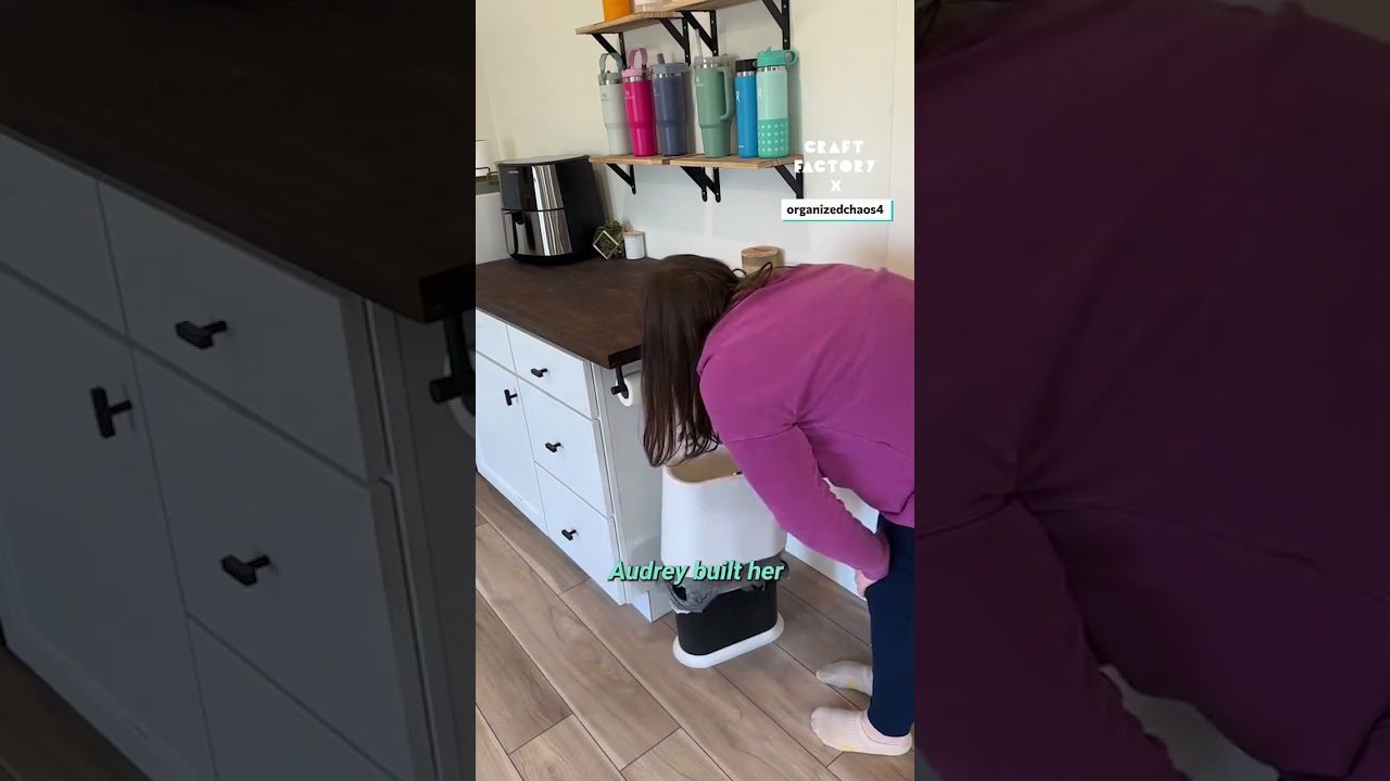 Moteris lenkiasi prie virtuvės šiukšliadėžės, šalia baltos spintelės ir lentynos su termopuodeliais