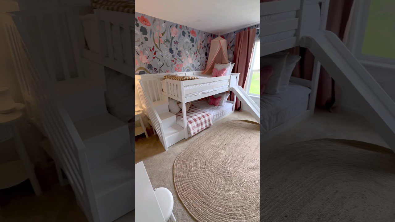 Baldais apstatytas vaikų kambarys su baltais dvivėriais lova laiptais, čiuožykla ir gėlėta siena