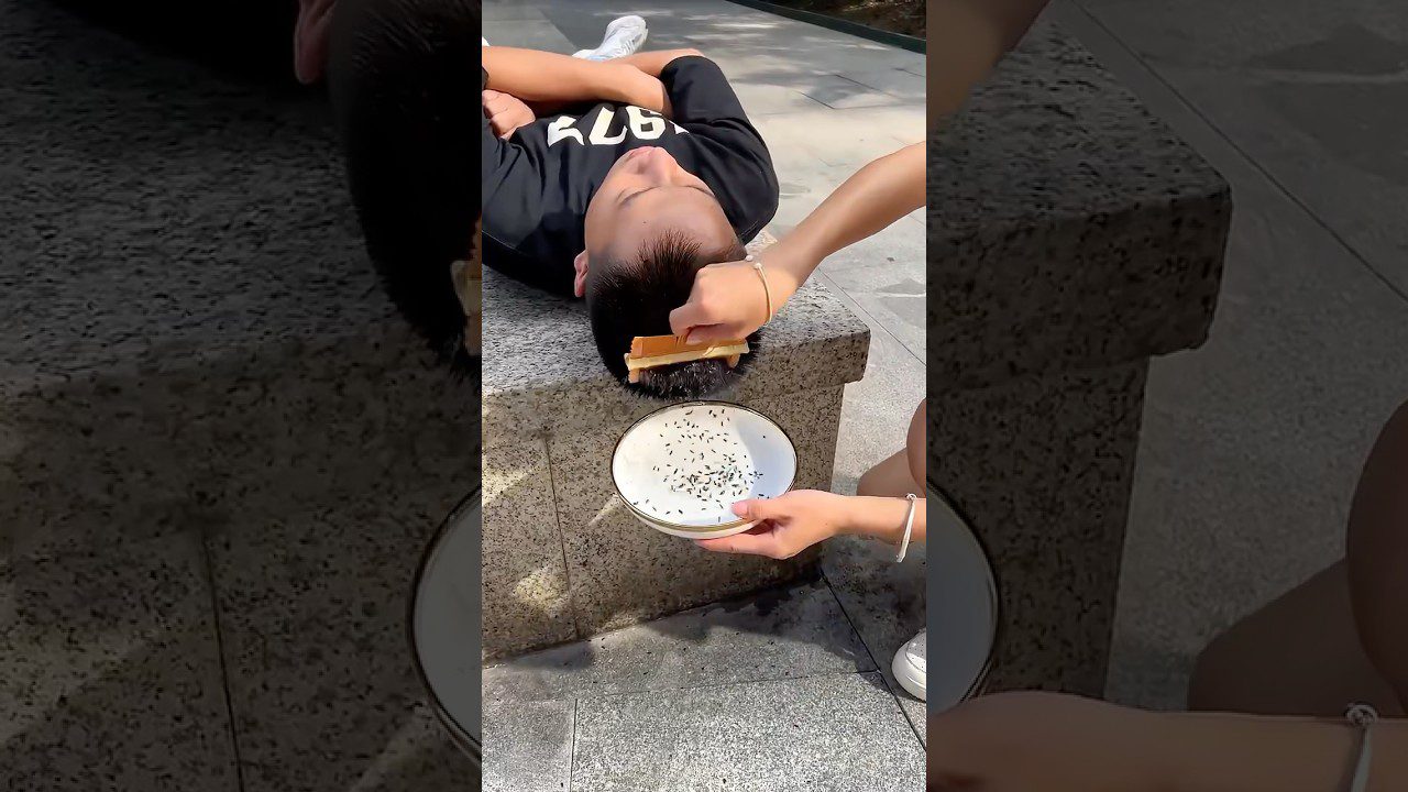 Jaunuolis guli ant akmens su užrišta galva, šukuojamas ranka virš lėkštės.