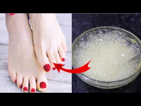 Raudonais nagais lakuoti kojų pirštai šalia stiklinės putojančio bičių vaško tirpalo.