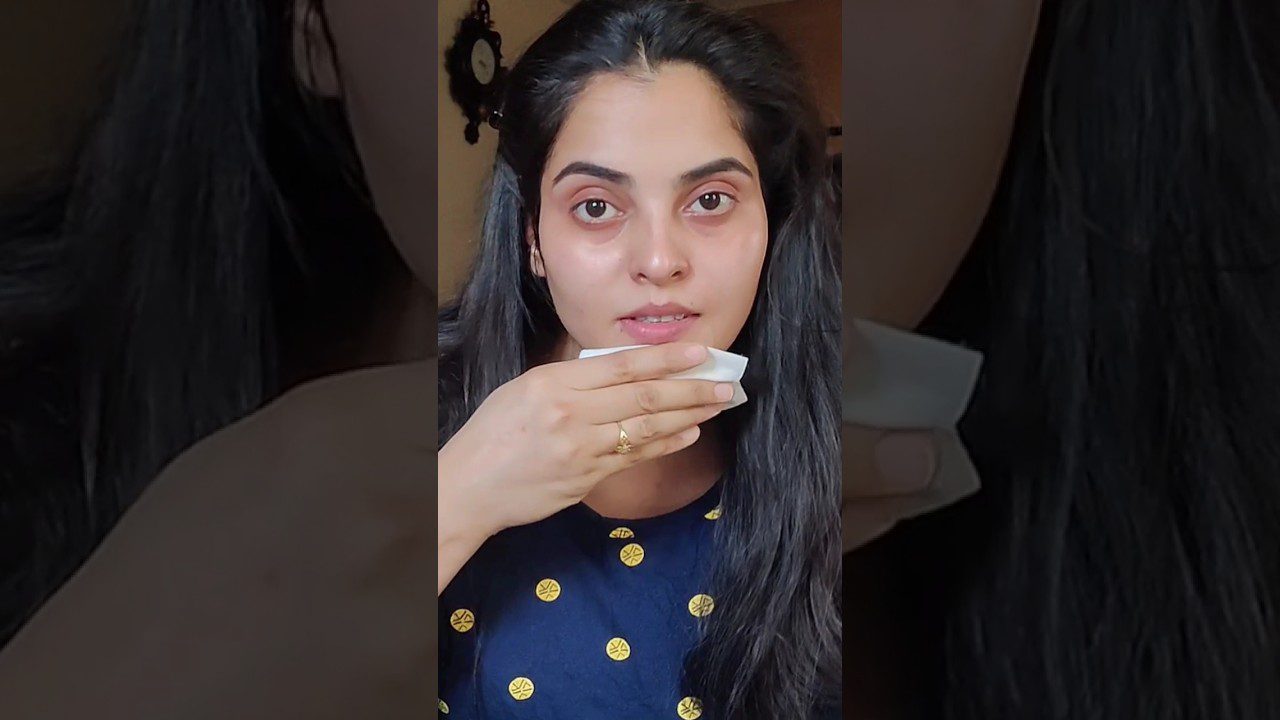 Jauna moteris nuvalo veidą servetėle, dėvi tamsiai mėlyną džemperį su geltonais apskritimais