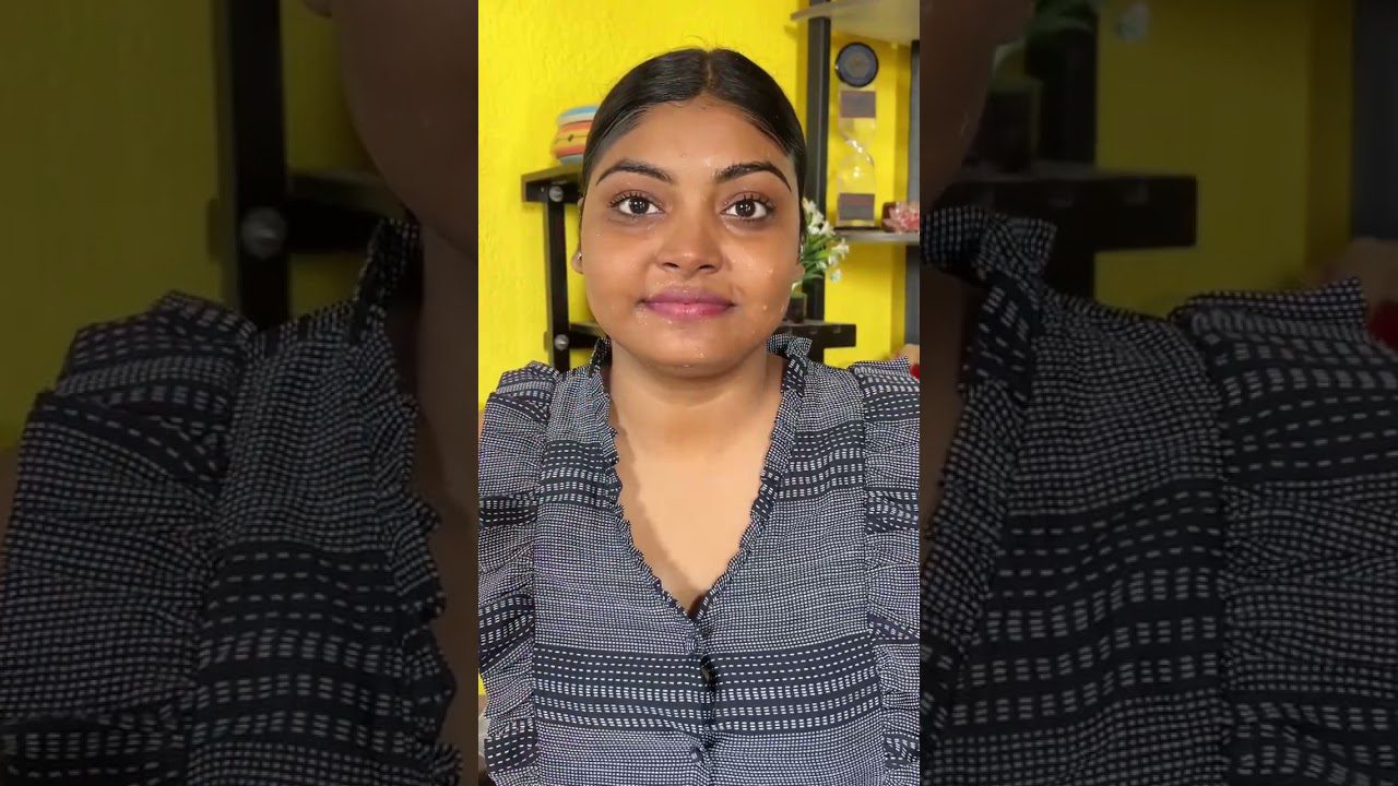 Jauna moteris su tamsiai surištais plaukais ir dryžuotu šviesiai tamsiu viršutiniu drabužiu, geltona fono siena