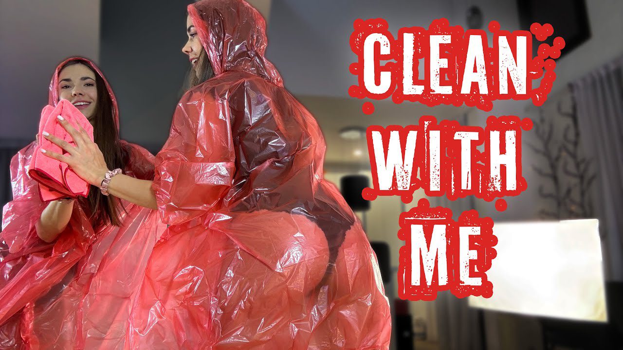 Moteris vilki raudoną plėvinį, valydama veidrodį rožine šluoste, užrašas „Clean with me“