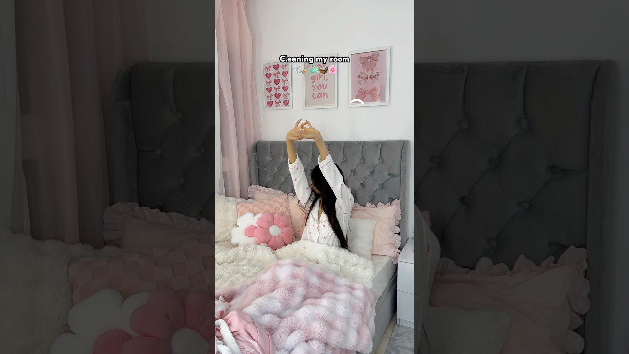 Mergina susirangusi ant lovos su rožiniais pagalvėmis, ant sienos rėmeliai su užrašu „girl you can“