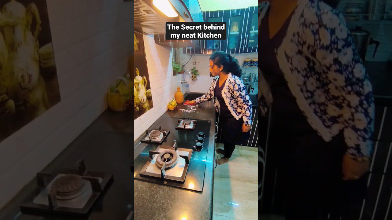 Moteris tvarko virtuvės stalviršį šalia dujinės viryklės ir indų spintelių