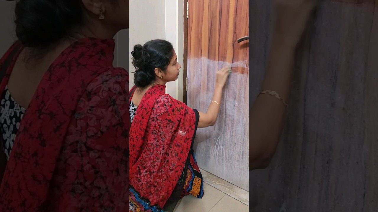 Moteris raudonu šaliu valo medines duris su šveitimo priemone, klūpėdama ant grindų