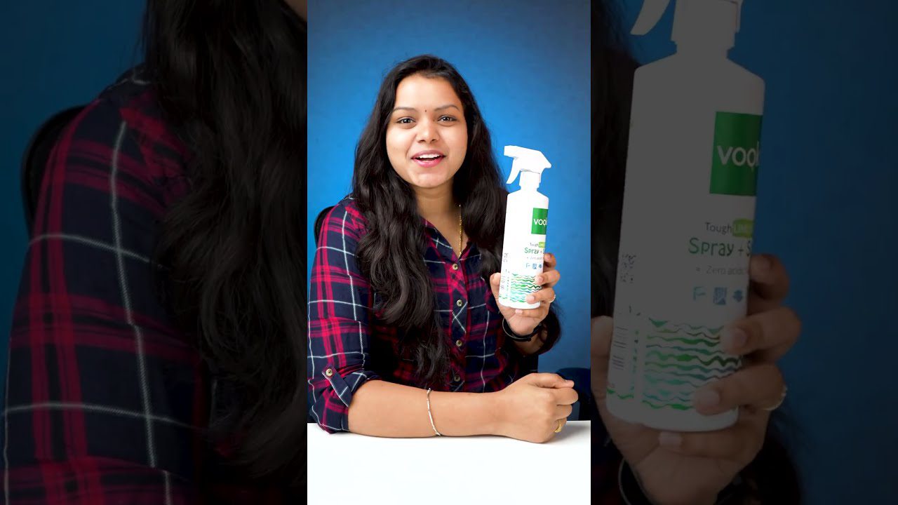 Moteris laikanti balto purškalo buteliuką su žaliu lipduku ir plačiai šypsosi