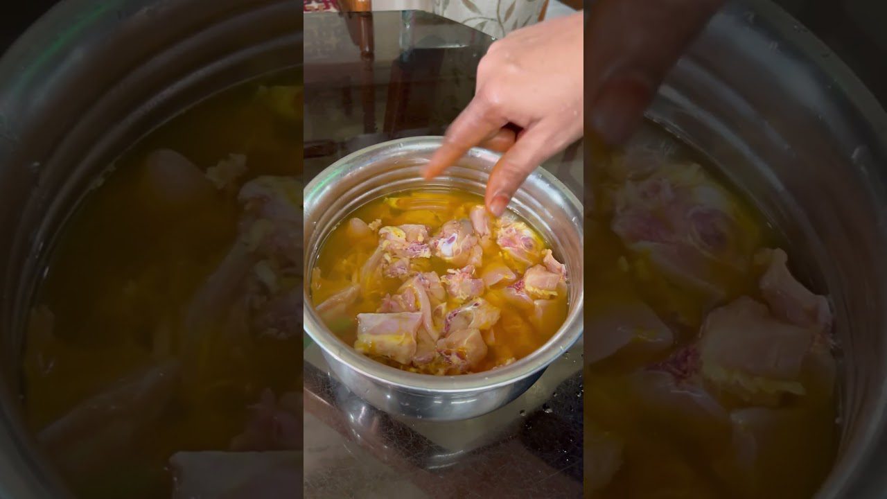 Rankos deda žalią vištieną į metalinį puodą su sultiniu ir prieskoniais.