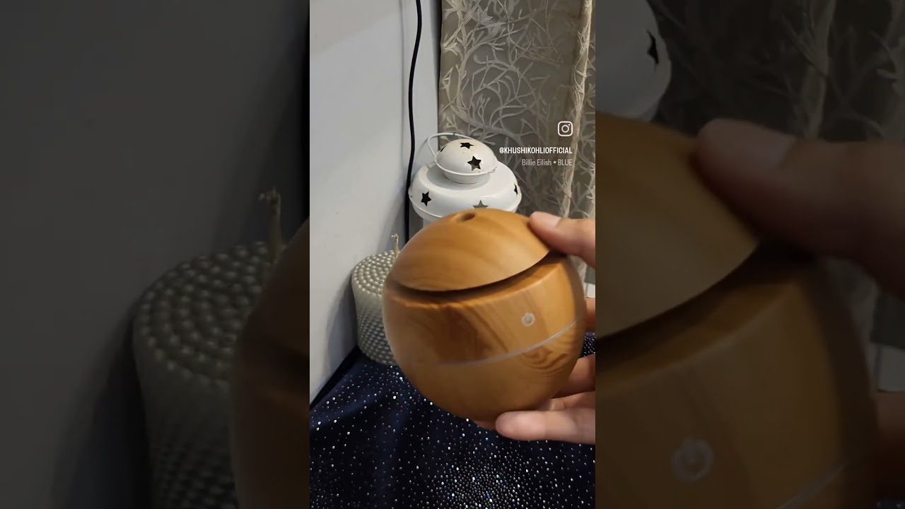 Rankus medinis eterinių aliejų difuzorius ant stalo, foninė žvaigždžių lempa.