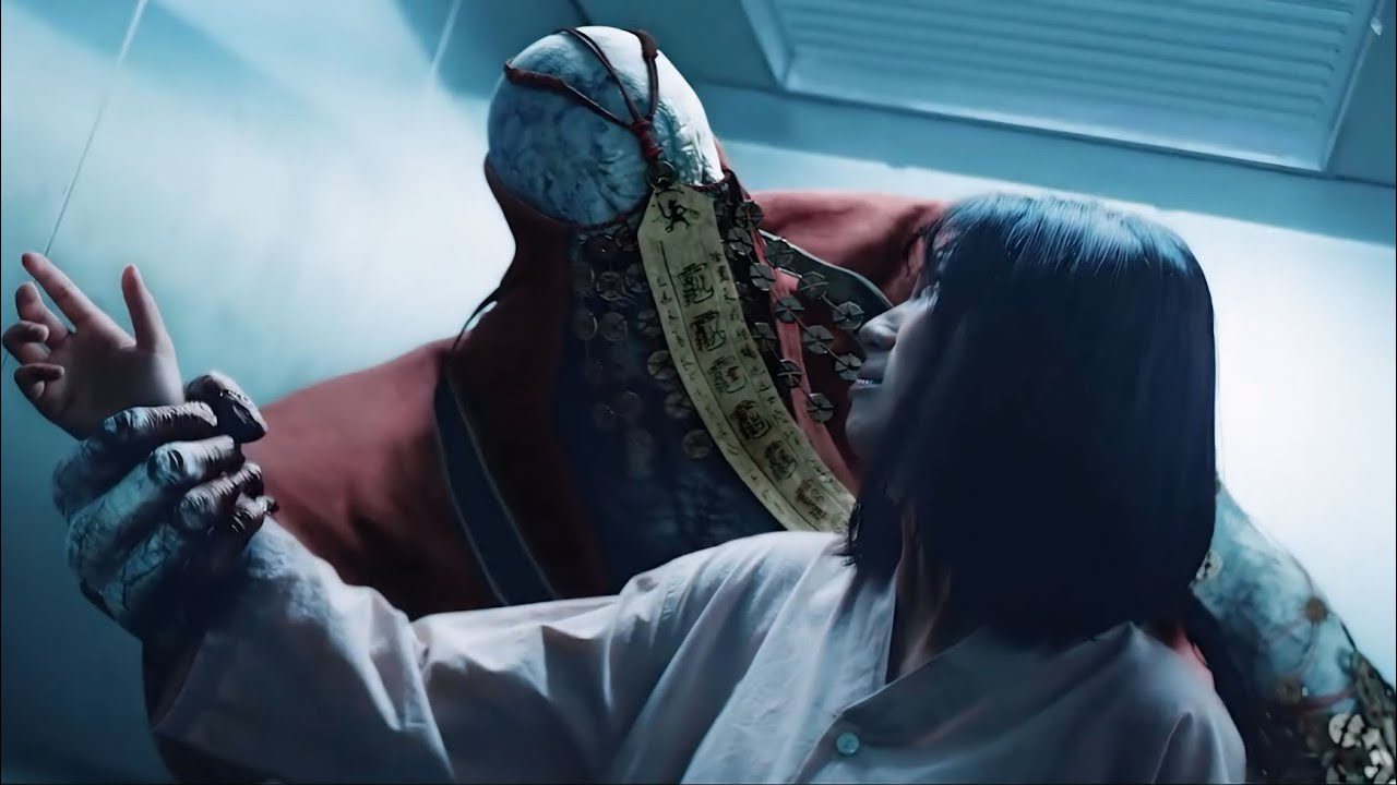 Moteris laikoma didžiulio siuvinėto figūros su kinų talismanais rankose.