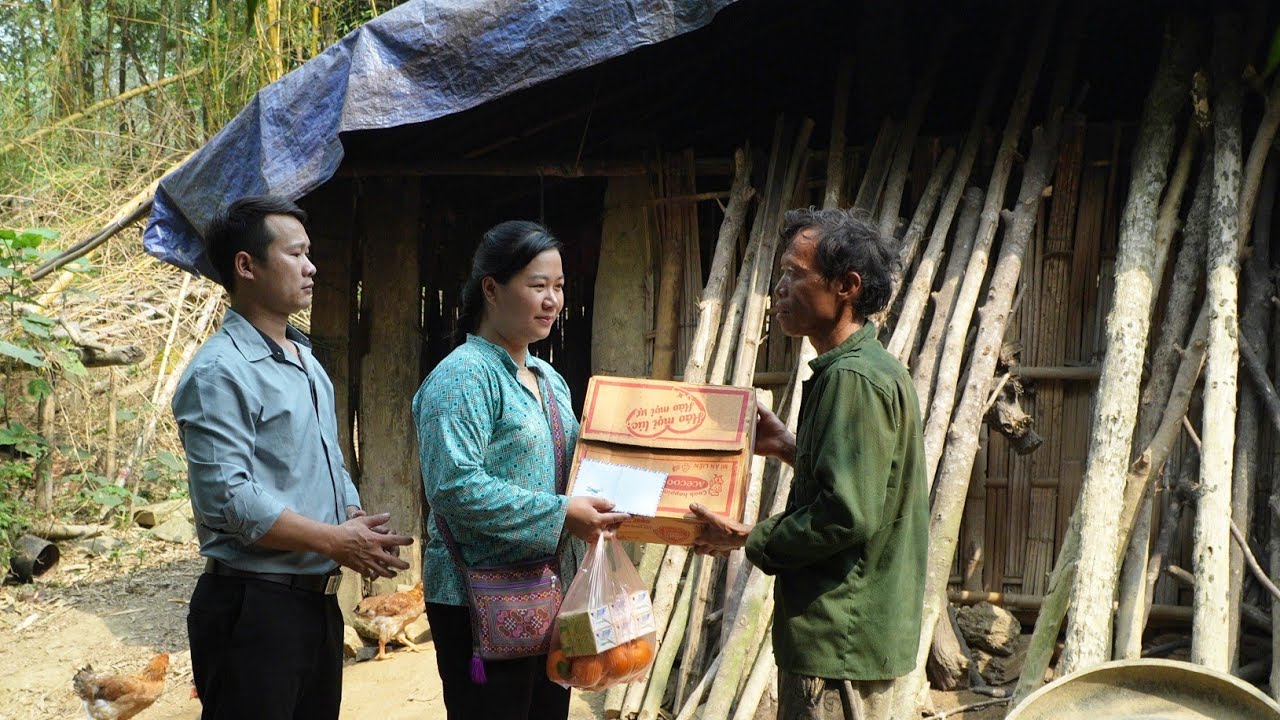 Moteris ir vyras perduoda maisto dėžę bei vaisius vyriškiui prie trobų