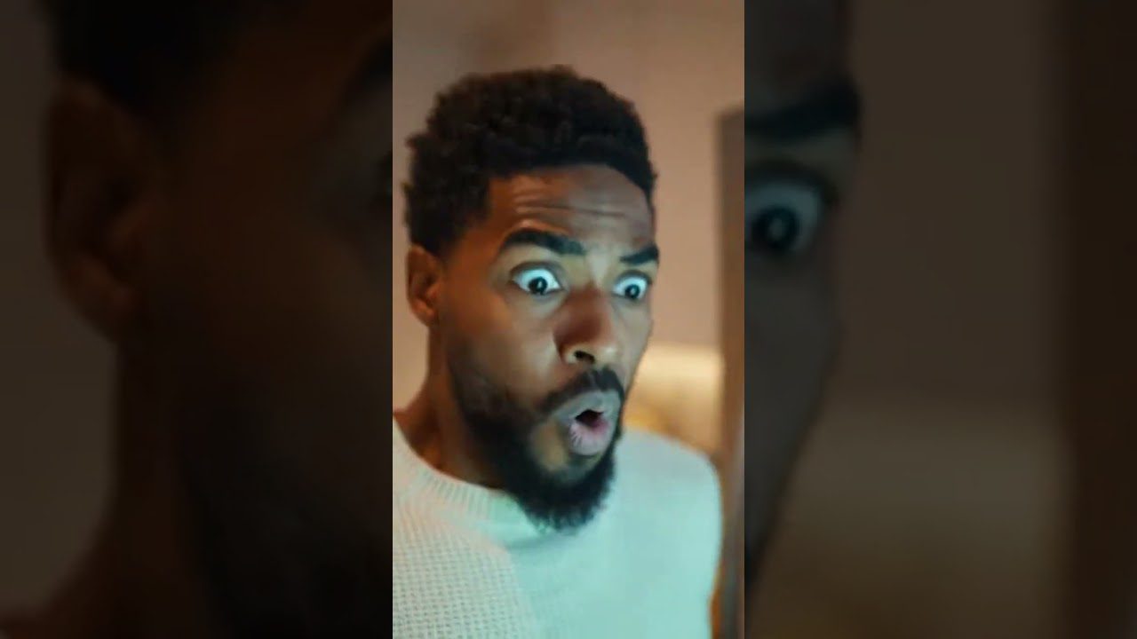 Vyras su barzda ir plačiomis akimis žiūri nustebęs į ekraną