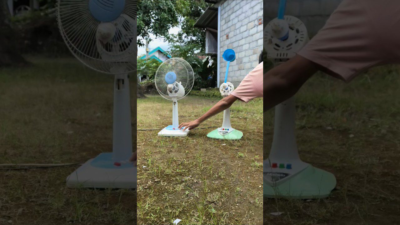 Du staliniai ventiliatoriai ant žolės, žmogaus ranka spaudžia mygtuką vienam.