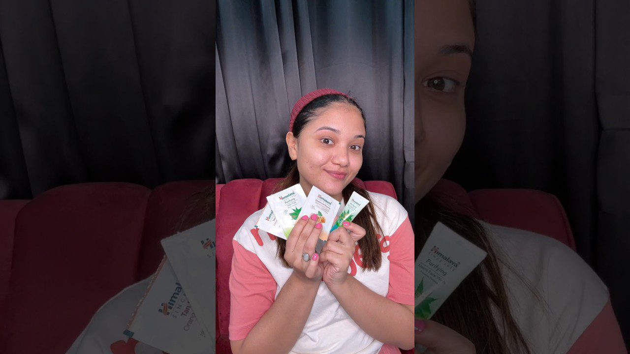 Moteris su plaukų juosta laiko veido priežiūros produktų mėginius ir šypsosi kamerai