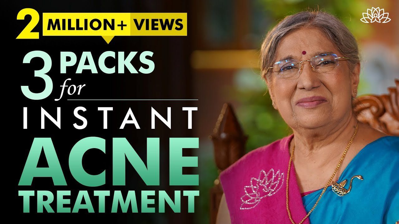 Vyresnė indė moteris su akiniais ir tradicine sari, šypsosi prie teksto apie spuogų gydymą