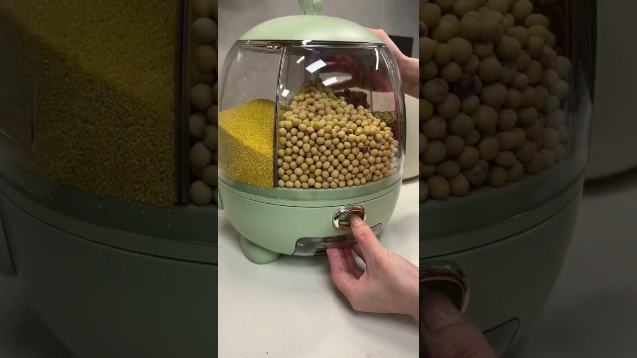 Žalias grūdų dozatorius su keliomis skyrelėmis, ranka paspaudžia metalinį mygtuką.