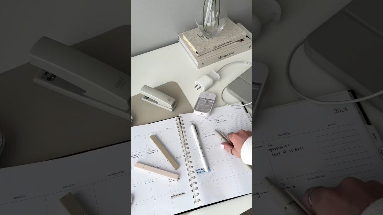 Moteriškos rankos rašo kalendoriuje ant stalo su segtuvu, pakrovele ir knygomis.