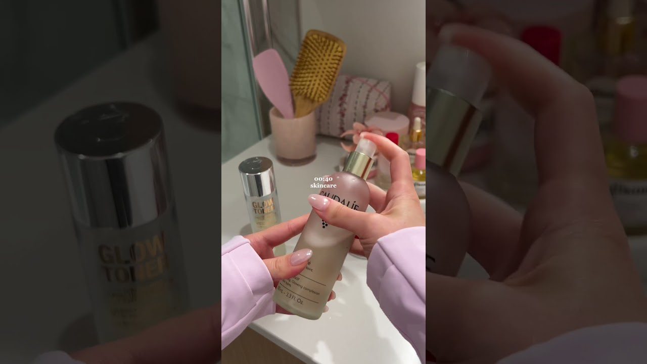 Ranka laikanti veido purškiklį prie vonios kriauklės su kosmetika fone