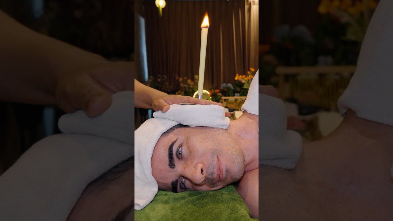 Vyras guli veidu į šoną su ranka uždėta ant galvos ir degančia žvake virš kaklo