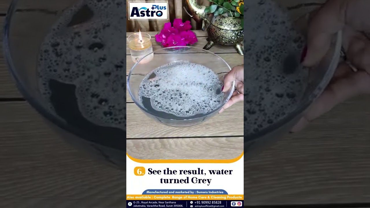 Stiklinis dubuo su pilkai drumzlinu putotu vandeniu ir degtukine žvakė fone