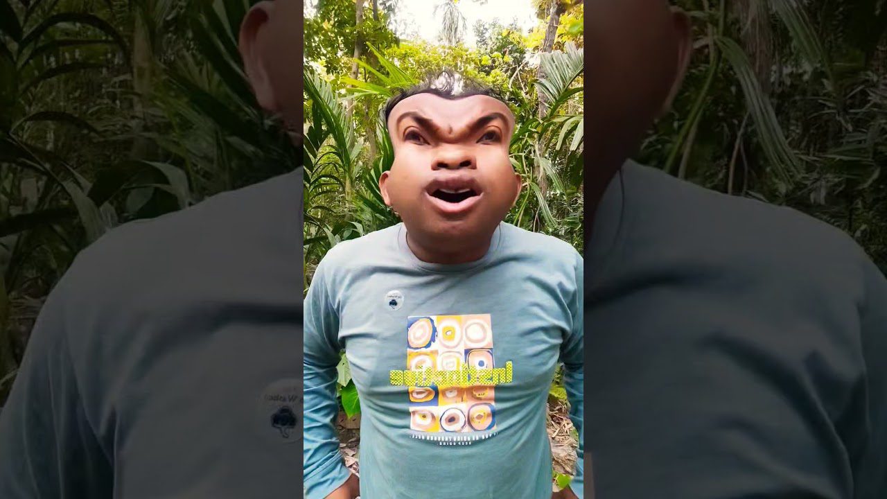 Vyras lauke su iškraipyta veido filtro kauke ir mėlyna marškinėliais su raštu