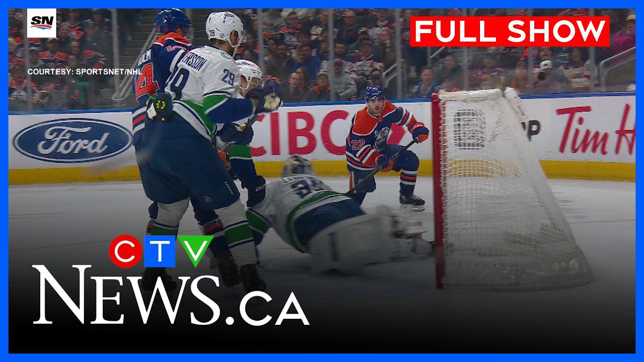 Edmontono "Oilers" žaidėjas prie vartų metimu įvartį mėginančiam sustabdyti Vankuverio "Canucks" vartininkui.