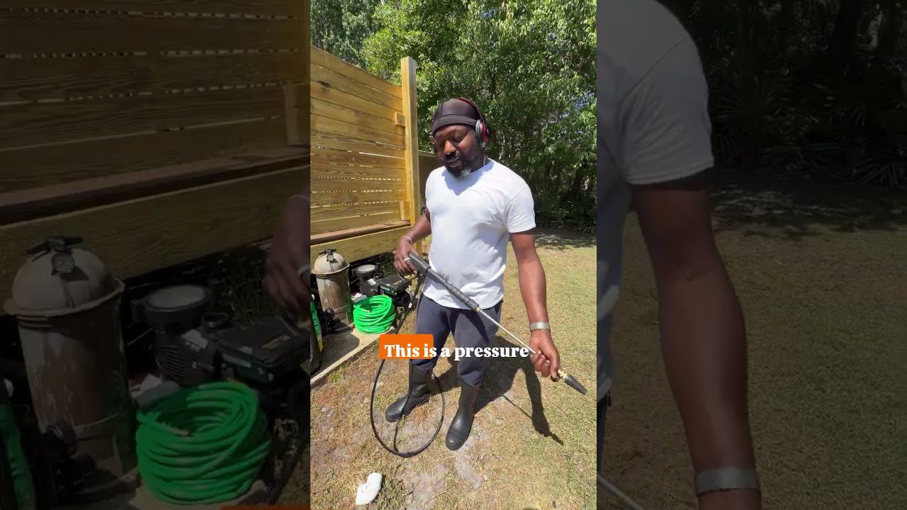 Vyras su ausinėmis lauke laiko aukšto slėgio plovimo antgalį šalia žalių žarnų ir įrankių