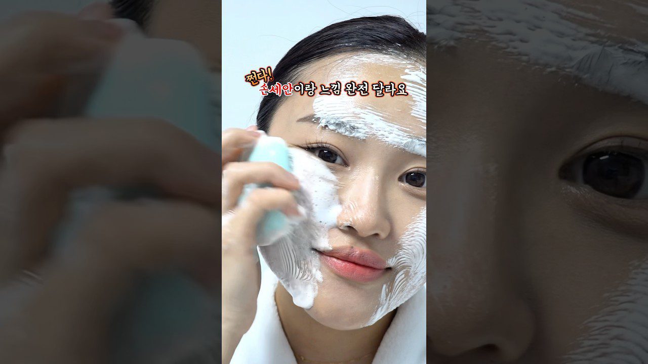 Moteris tepa putojantį veido prausiklį su elektrine šepetėlio galvute ant veido