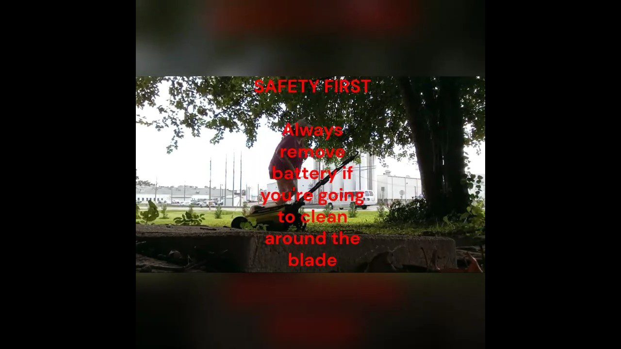 Vyras prižiūri žolės pjovimo įrankį po medžiu; užrašas „Saugumas pirmiausia: nuimkite bateriją prieš valant ašmenis“