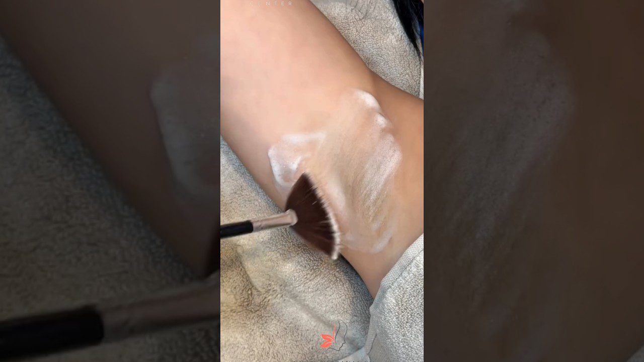 Rankos šepečiu tepama balta depiliacijos pasta ant žmogaus pėdos kulno odos